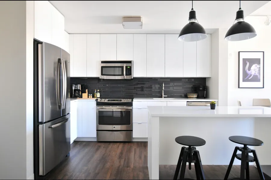 Clean white kitchen with island, stools and stainless appliances